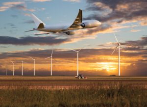 A plane flying over some wind turbines.