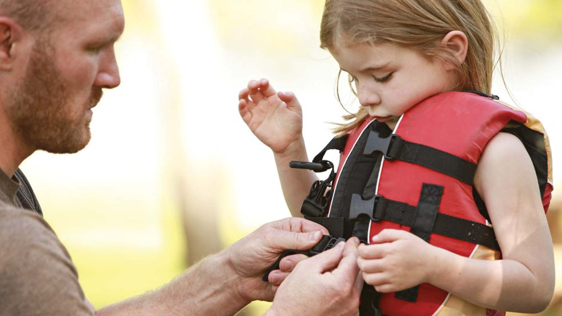man giving a life jacket on a child
