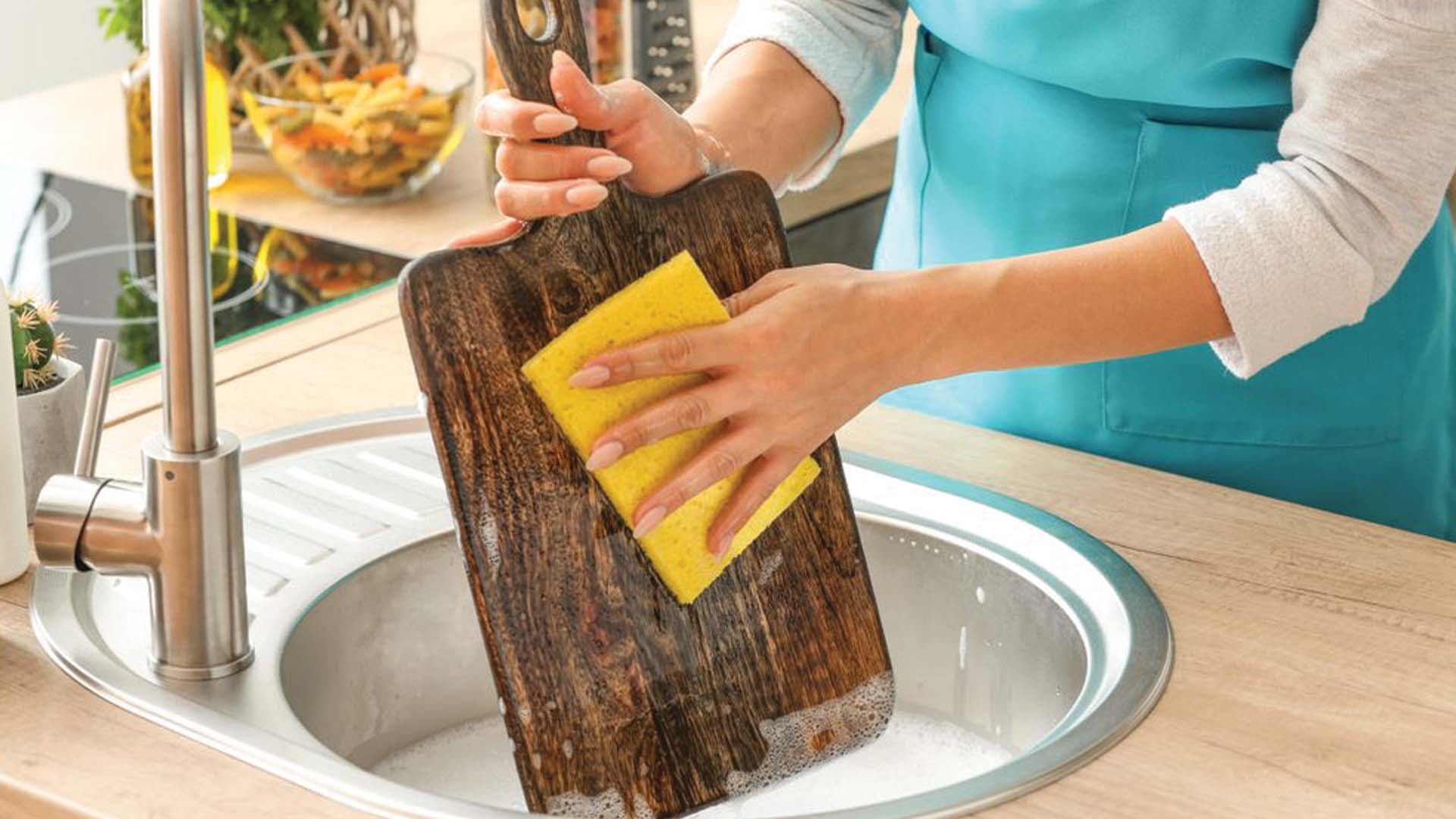 Woman making cutting board more hygienic by cleaning it