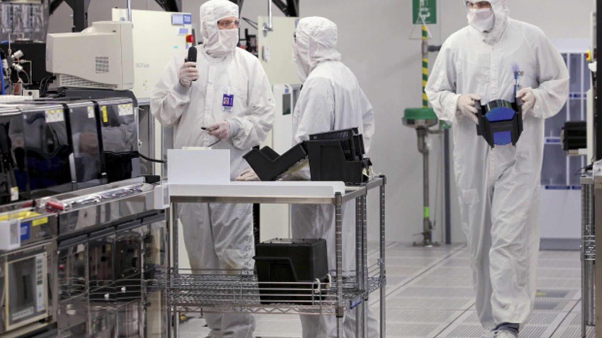 Workers prepare to load a silicon wafer machine in a clean room at the Texas Instruments semiconductor fabrication plant in Dallas, Texas; Photo Credit: Bloomberg News