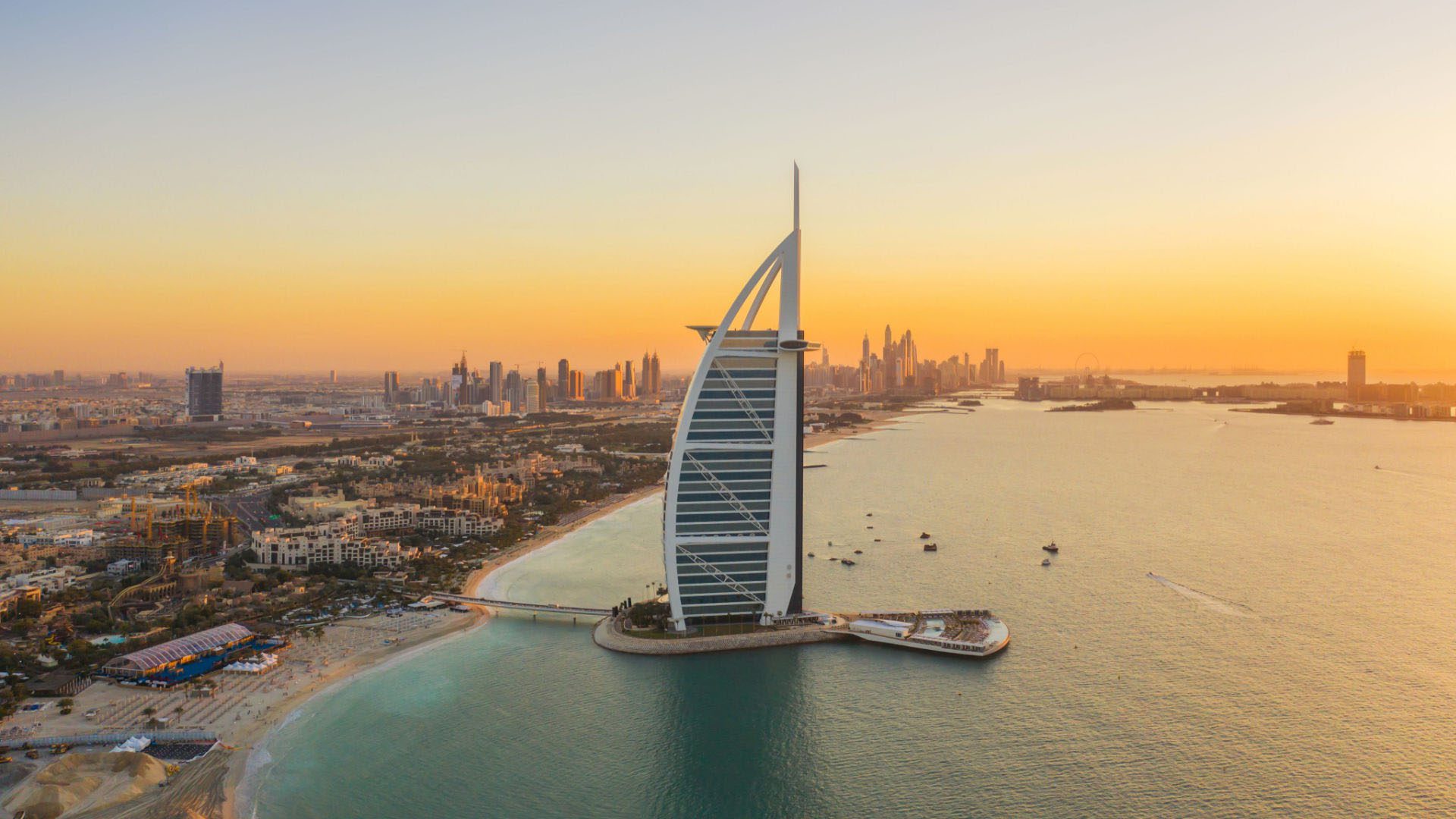 Dubai’s Burj Al Arab hotel at sunset over the city's skyline