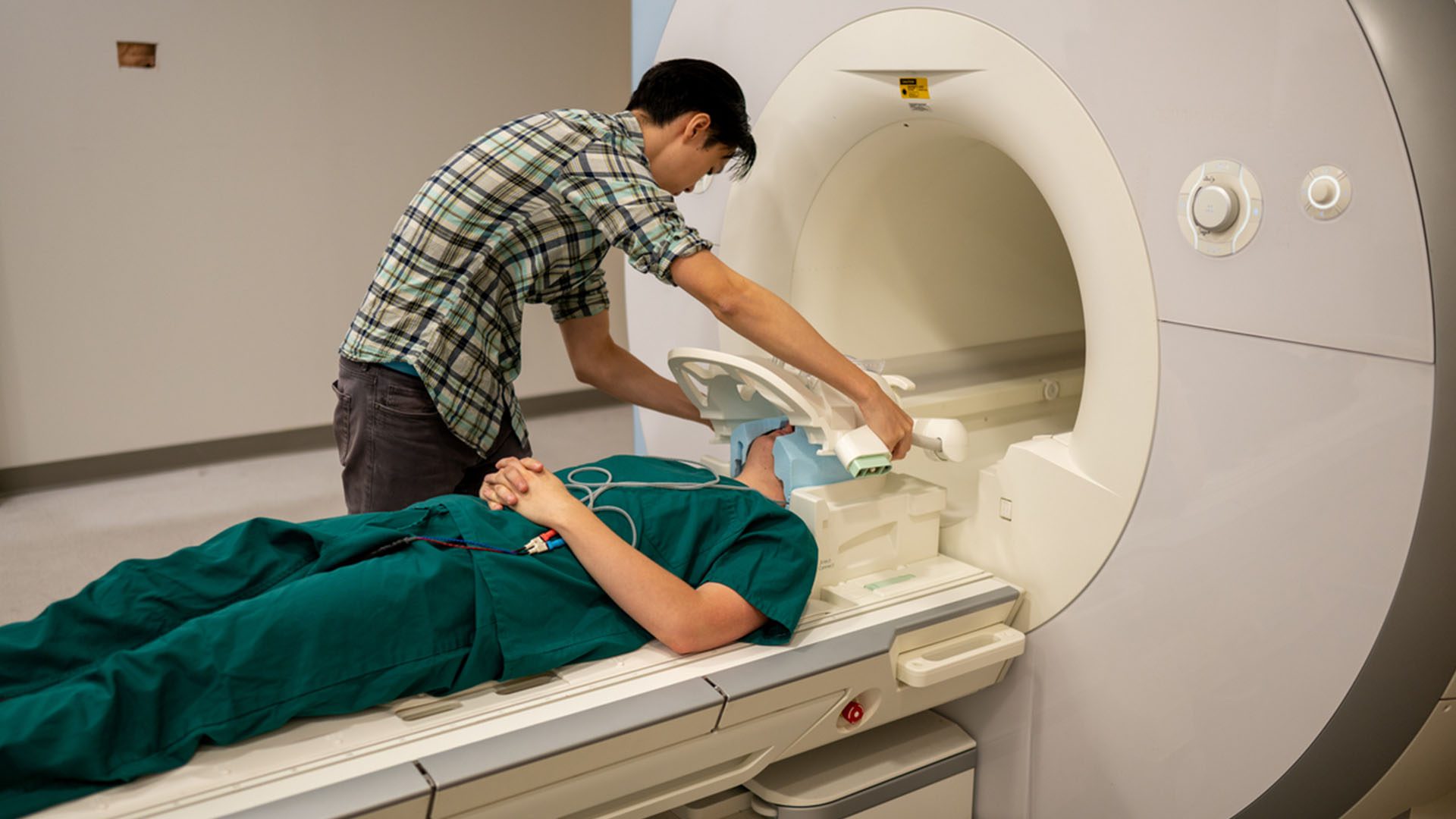 Ph.D. Student Jerry Tang prepares to collect brain activity data in the biomedical imaging center at the University of Texas at Austin